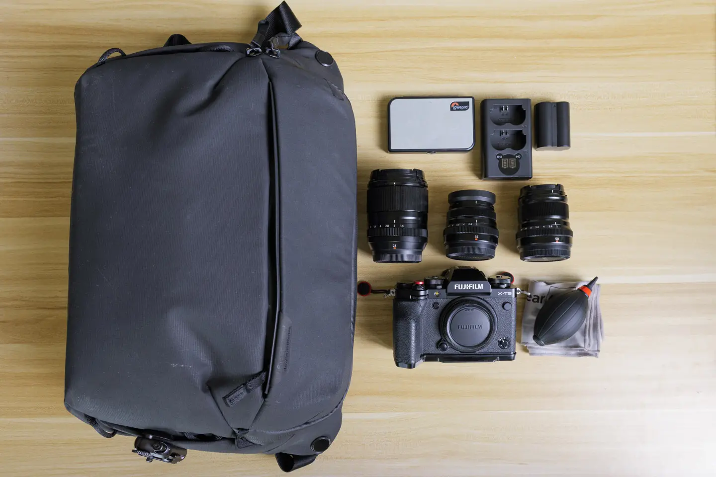 a flat lay of a fujifilm xt5 and some small prime lenses.