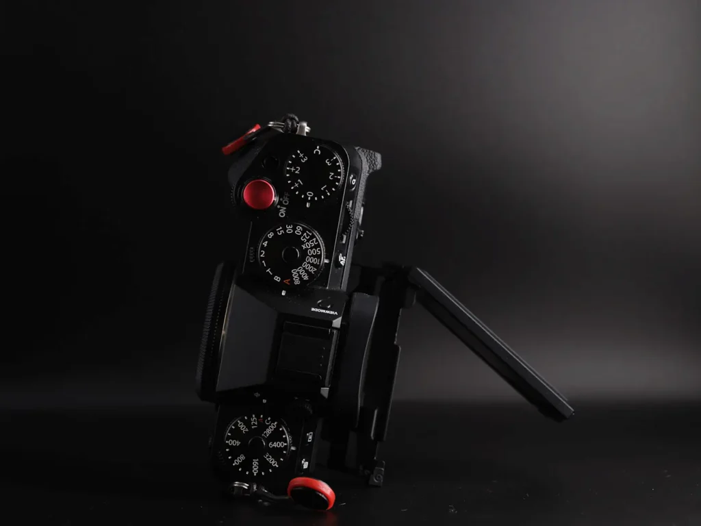 Fujifilm X-T5 camera with its rear LCD screen opened to show the 3-wat tilting mechanism. Photographed on a black background in dramatic light. 
