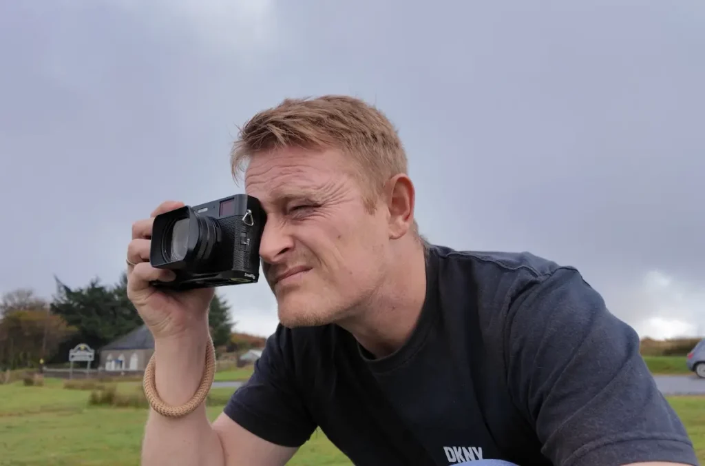 a photographer holds the Fujifilm X100Vi camera to his eye on Dartmoor.