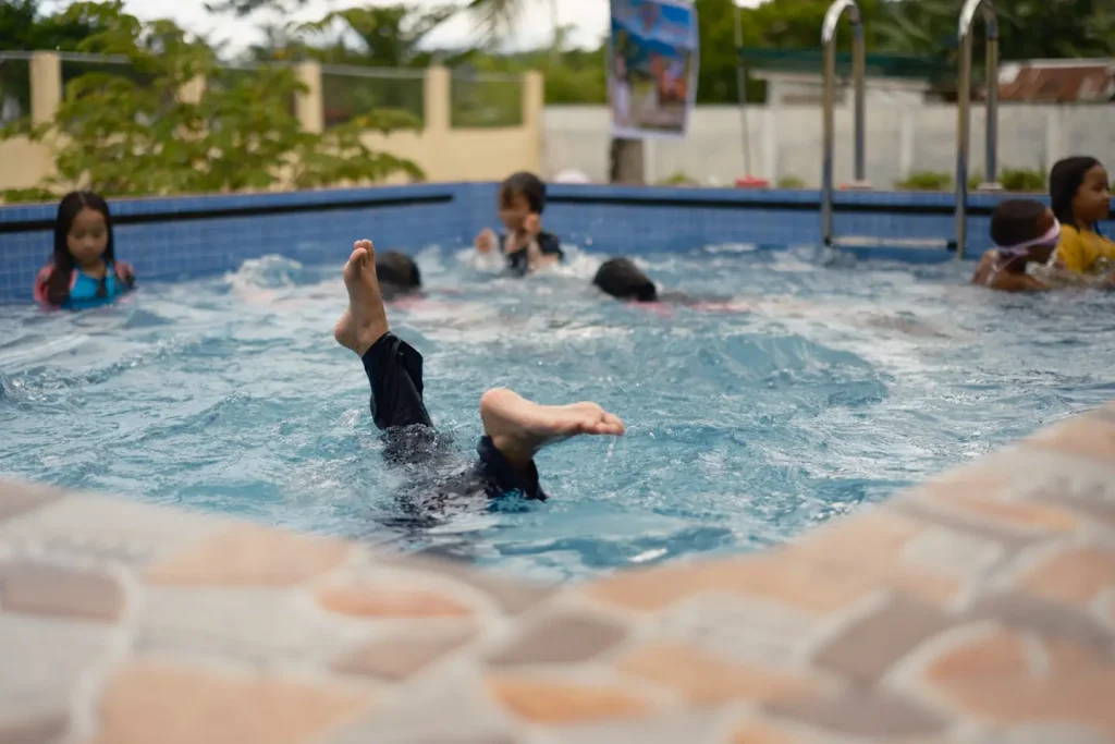 A photo of children playing in a swimming pool. The photo was taken with the Fujifilm 23mm 1.4WR lens to show how the auto focus of the lens performs in a busy environment.