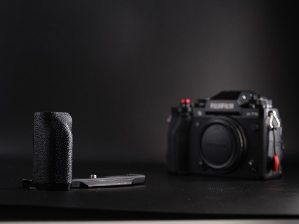 Smallrig L shaped Grip for the Fujifilm X-T5 photographed next to the camera on a black background in dramatic light to show the camera accessory.