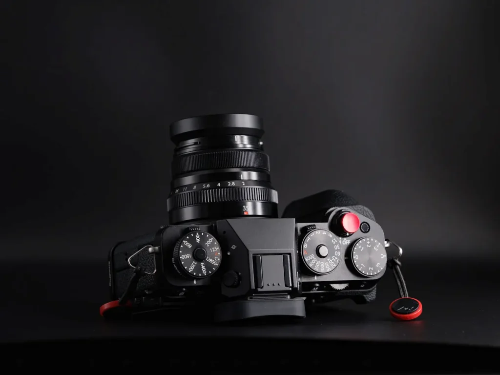 Fuji X-T5 with the Fujifilm 35mm f2 lens attached. Photo shows the top view of the camera on a black background in dramatic light.