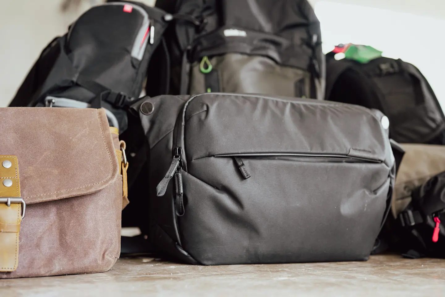 S pile of lots of camera bags of all different kinds including those from Peak Design, Lowepro, Manfrotto and others.