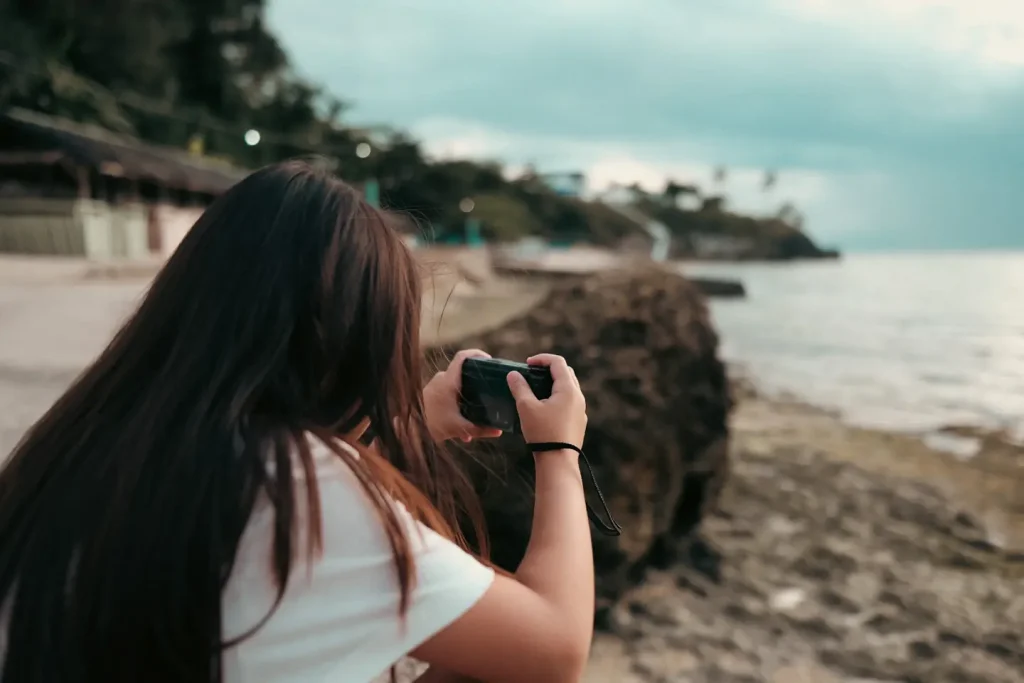 A young girl using her Ricoh GRIIIx camera at a beach in the Philippines. 