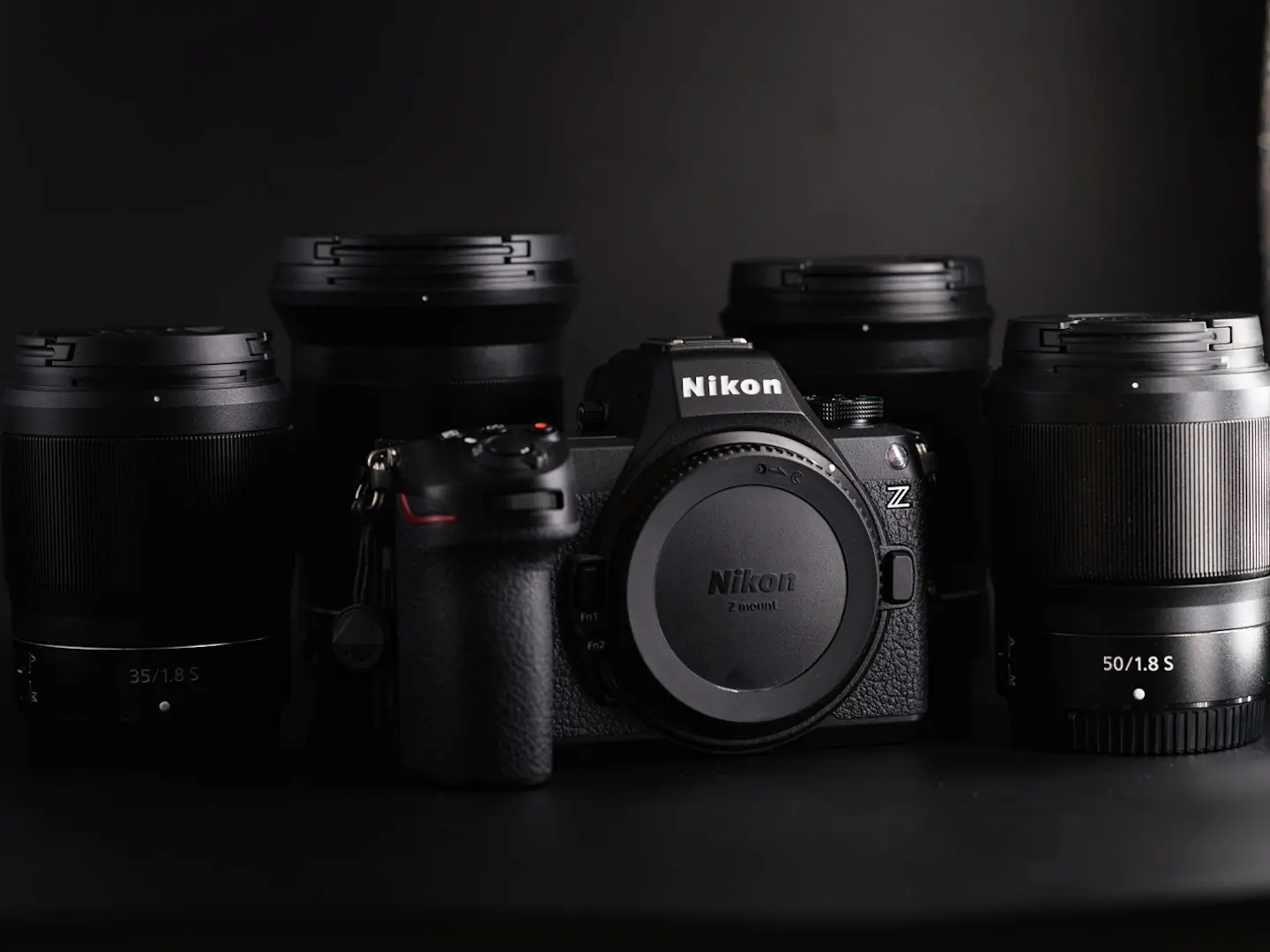 Nikon Z6 III camera surrounded by NIKKOR Z 35mm f/1.8 S, 50mm f/1.8 S and other S-line lenses on a dark background.