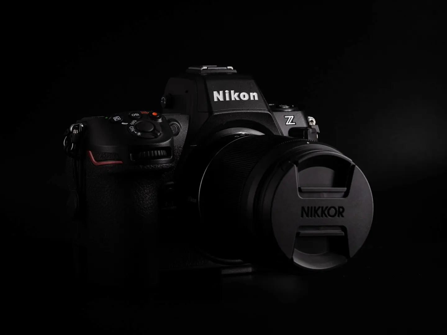 A Nikon Z8 camera with Nikon Z 35mm 1.8S prime lens attached. Photographed on a very dark black background in dramatic light.