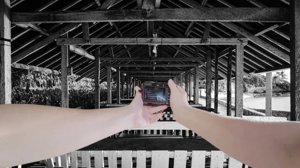 A POV photo of shooting the Fujifilm X100VI camera at the beach with a persepctive looking through the structure of the beach huts. 