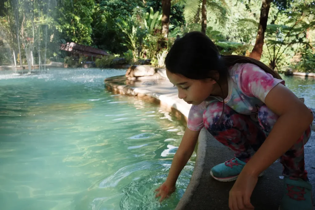 A 9 year old girl moving her hand in to a cold spring pool in the Philippines while on vacation. Photo taken on the Ricoh GRIV camera.