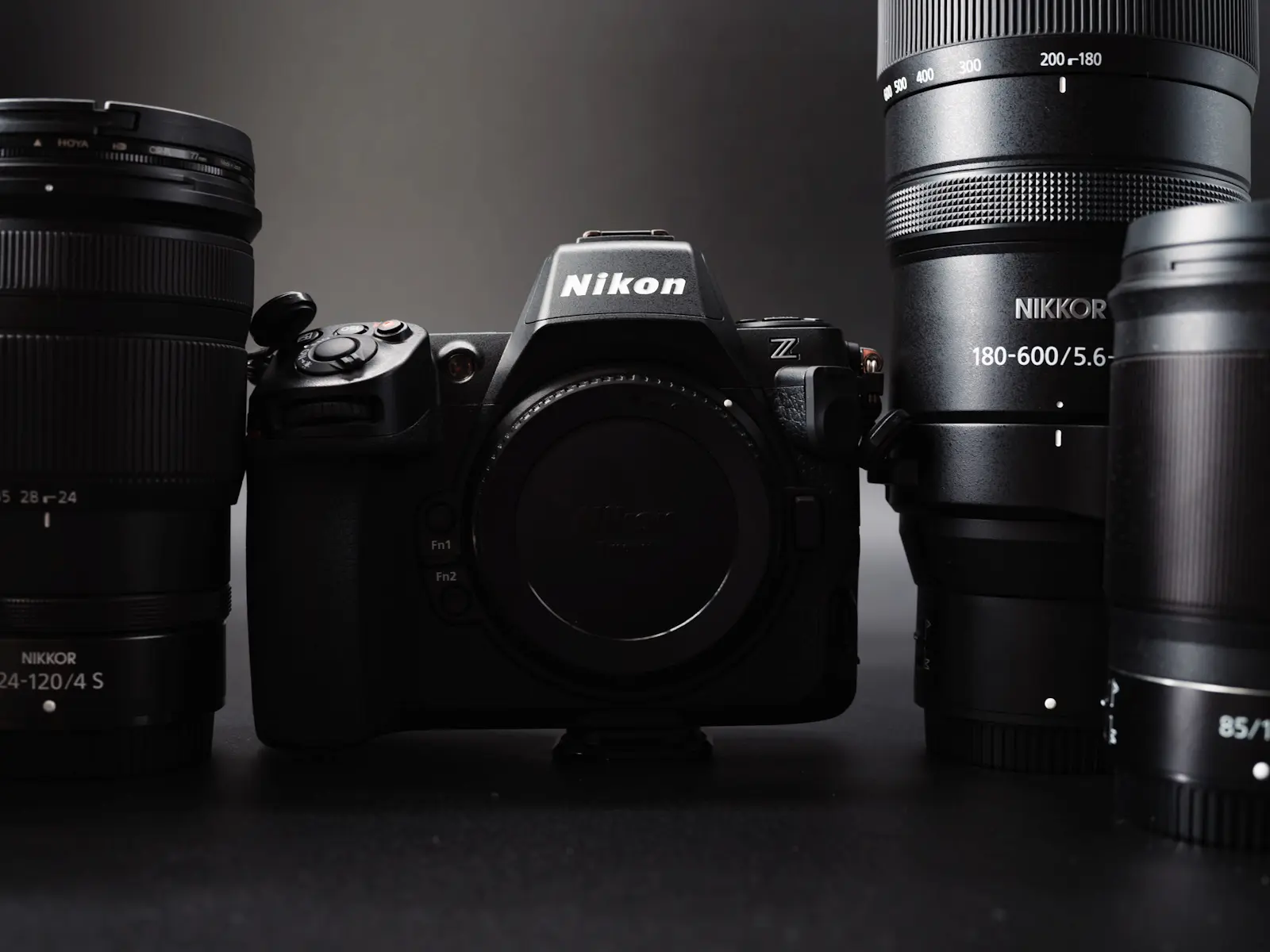 The Nikon Z8 camera surrounded by some of the best Nikon Z lenses. Photograph is taken against a black background in dramatic lighting.