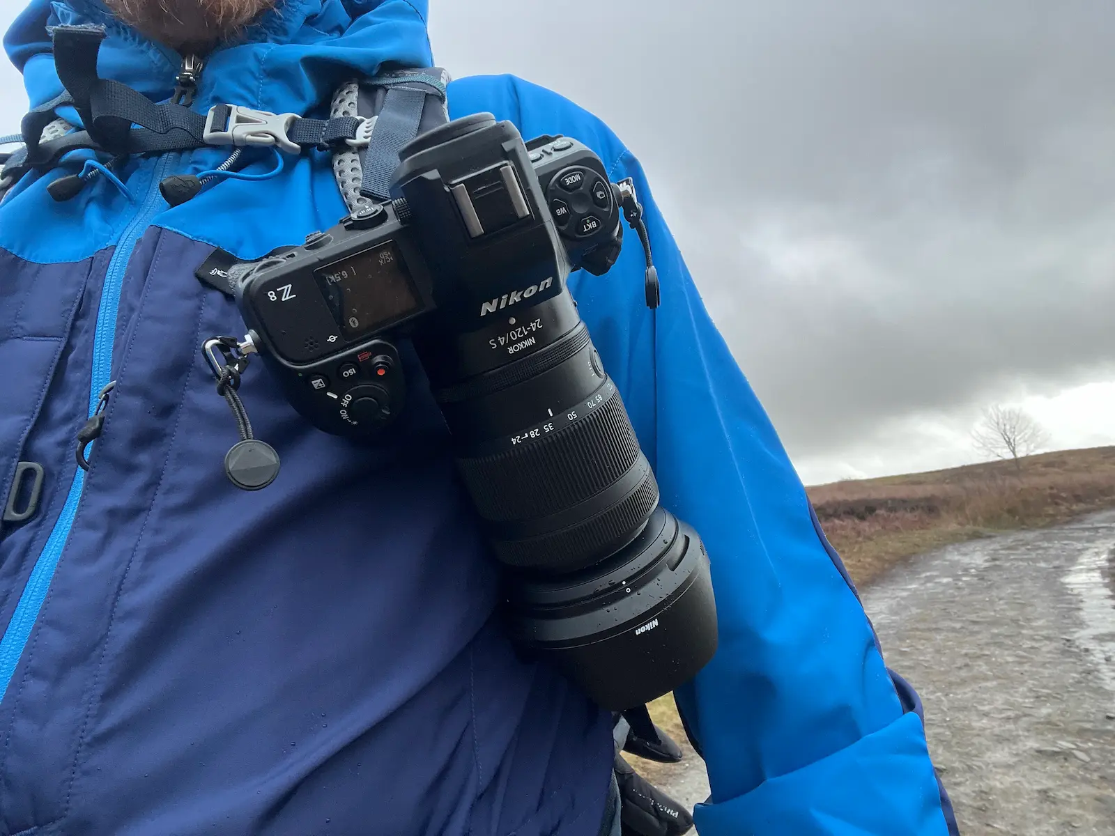 A photographer carrying the Nikon Z 24-120mm f/4S lens attached to a Nikon Z8 camera on a Peak Design Capture Clip.