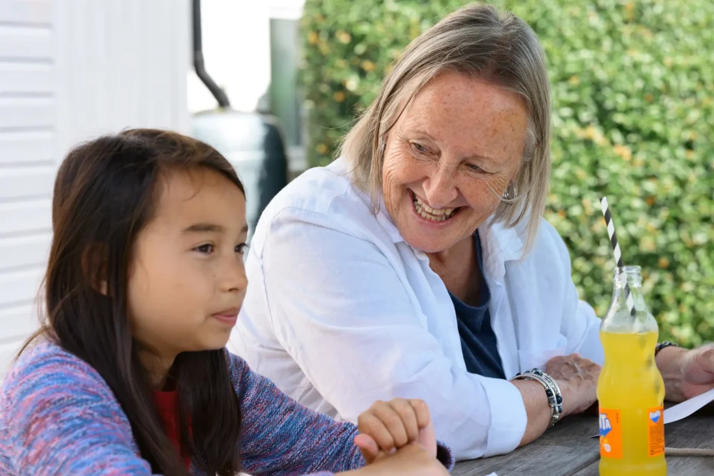 My mum and daughter sat at a picnic table at a pub in Auchterarder, Scotland having a drink and waiting for their lunch in sunshine. Photo is taken on the Nikon Z6III and 85mm 1.8S lens. 