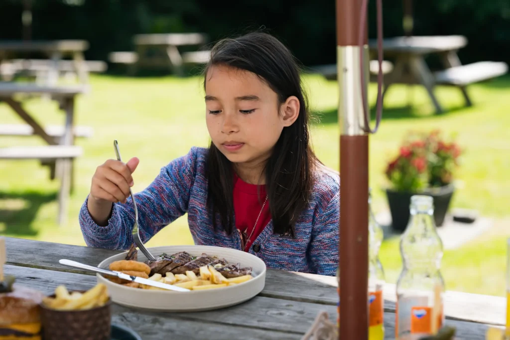 A photo of my eldest daughter, Sofia, eating steak and french fries while sat at a picnic table in a beer garden in Auchterarder in Scotland. 