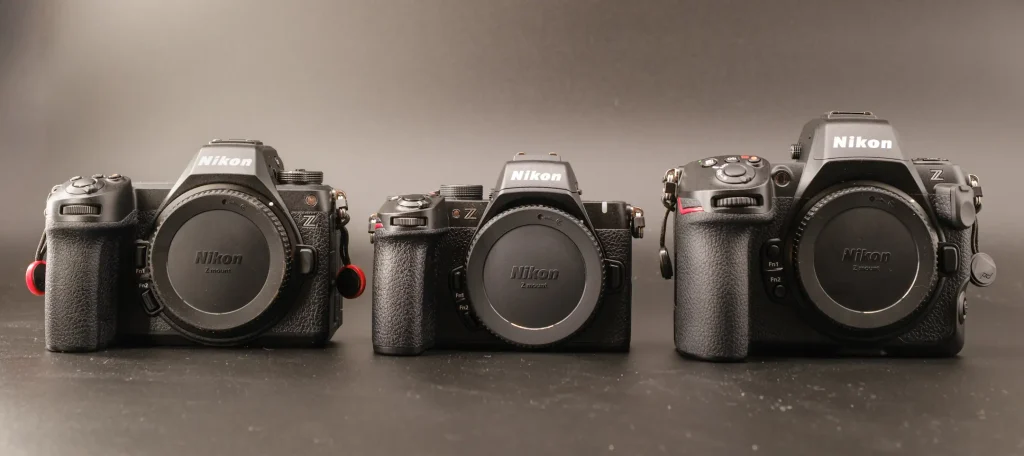 A Nikon Z50II with a Nikon Z6III to the left and a Nikon Z8 to the right of it. Photographed on a black background with sidelight.