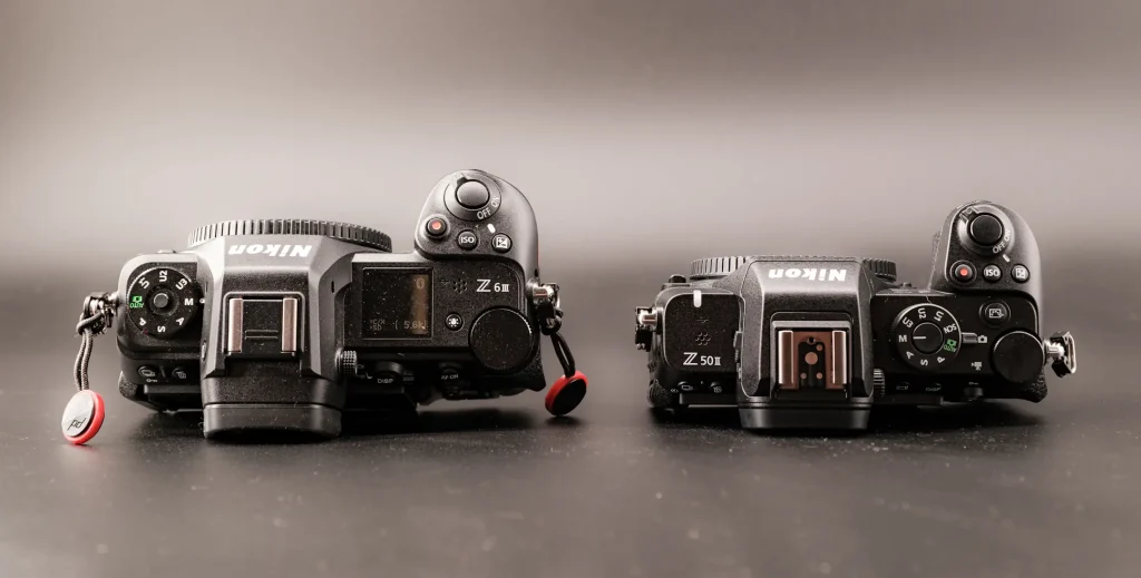 The top plate of the Nikon Z6III and Z50II next to each other to show the differences. Photo is taken on a black background.