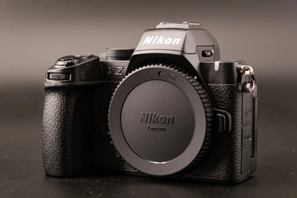 A Nikon Z50II camera photographed on a black background with side-light creating dramatic shadows.