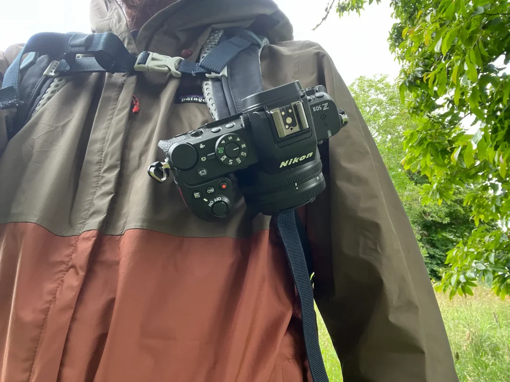 The Nikon Z50II shown attached to the Peak Design Capture Clip on the backpack of a photographer.