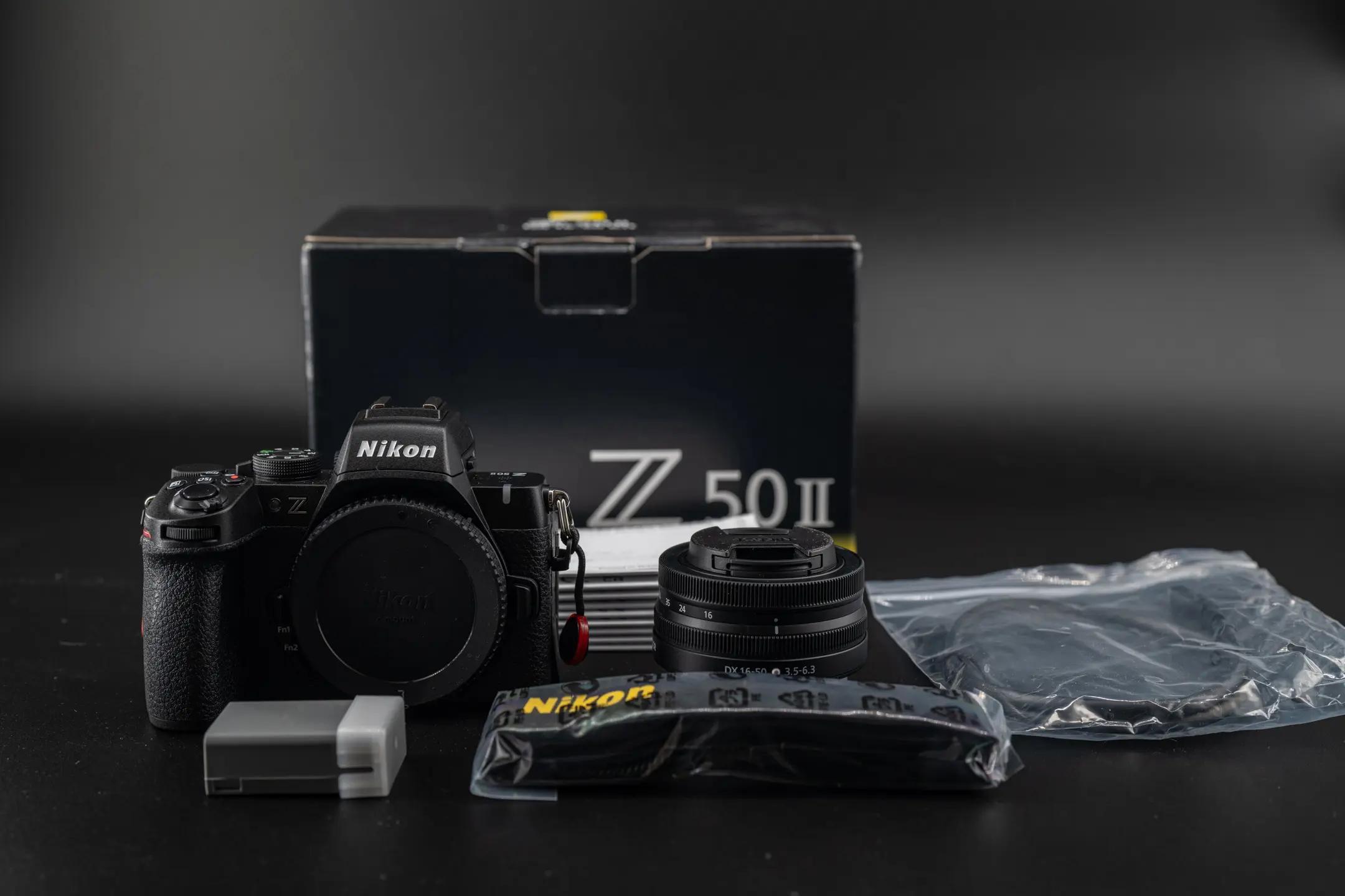 The Nikon Z50II and 16-50mm kit lens package contents laid out on a black background.