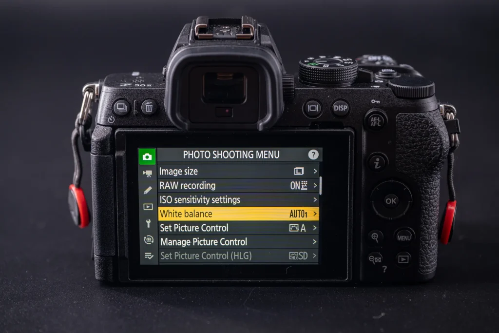 The rear of the Nikon Z50II camera with the LCD screen showing the white balance option highlighted in the Photo Shooting Menu.