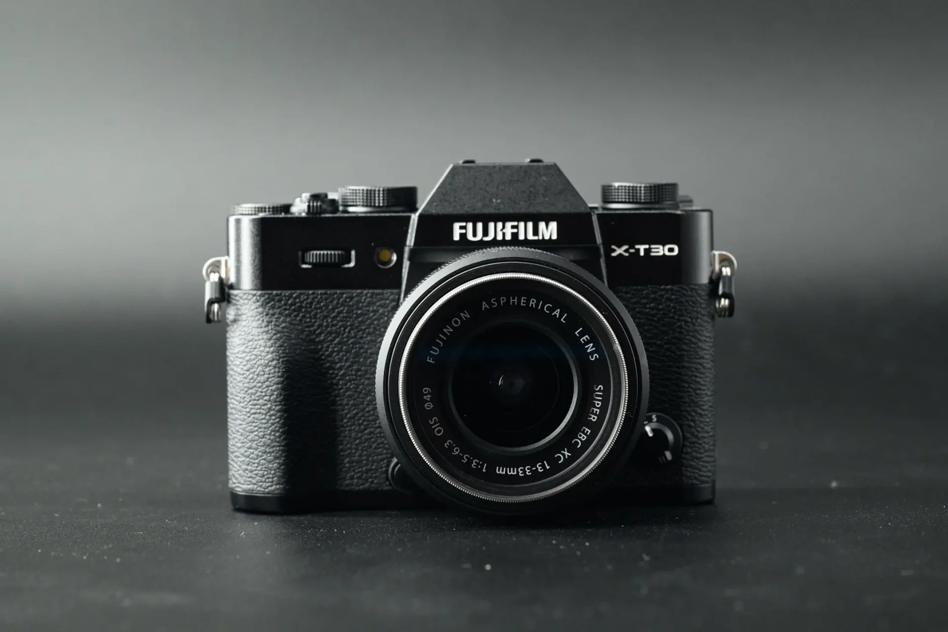 The Fujifilm X-T30 III camera with 13-33mm kit lens attached. Photographed on a black background with dramatic lighting.